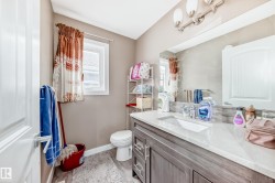 Bathroom featuring a single vanity with stone-look countertop, integrated sink, and wood-finish cabinetry - 