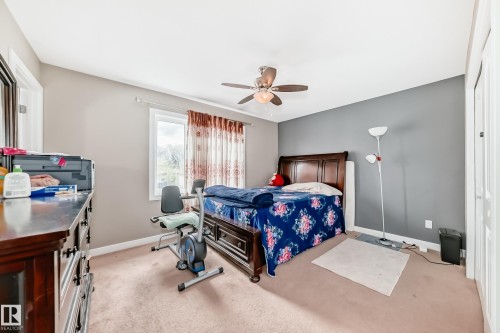 Bedroom featuring neutral-toned walls, a single window with curtain rods, a ceiling fan with integrated lighting, and carpeted flooring - 1 12833 123 Street, Edmonton, AB - Indoor Photo Showing Bedroom