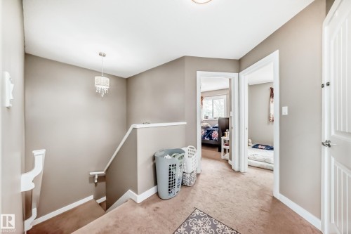 Upper-level hallway featuring a chandelier, white trim, and two paneled doors opening to additional rooms - 1 12833 123 Street, Edmonton, AB - Indoor Photo Showing Other Room