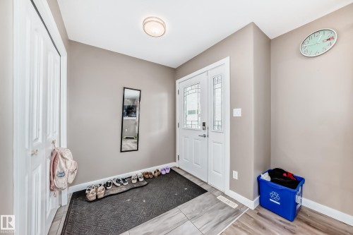 Entryway featuring a white door with decorative glass inserts, wood-finish flooring, and a flush-mount ceiling light - 1 12833 123 Street, Edmonton, AB - Indoor Photo Showing Other Room