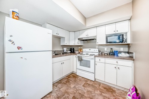 Kitchen featuring white cabinetry, laminate countertops, a white top-freezer refrigerator, a white electric range, and a built-in microwave - 1 12833 123 Street, Edmonton, AB - Indoor Photo Showing Kitchen With Double Sink