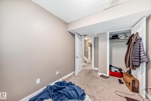 Bedroom featuring neutral-toned walls, carpet flooring, white baseboards, and a bi-fold closet with an interior shelf and hanging rod - 1 12833 123 Street, Edmonton, AB - Indoor
