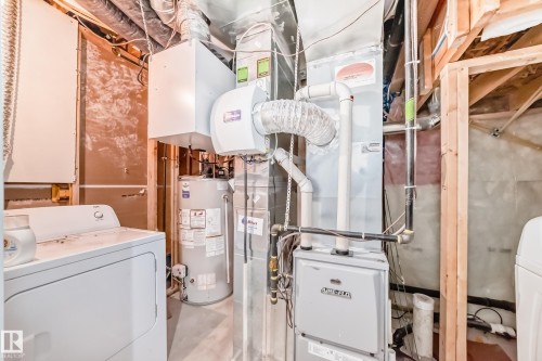 Dedicated utility area featuring a white washing machine, dryer, water heater, and furnace - 1 12833 123 Street, Edmonton, AB - Indoor
