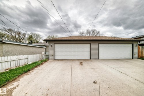Detached garage featuring two overhead doors, horizontal siding, and a shingle roof - 1 12833 123 Street, Edmonton, AB - Outdoor With Exterior