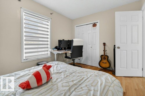 Room featuring a window with zebra blinds, wood-finish flooring, two-panel closet doors, and a six-panel door - 157 Kiniski Crescent, Edmonton, AB - Indoor Photo Showing Bedroom