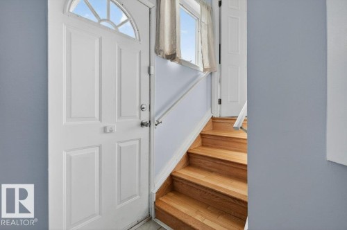 Entryway featuring a white paneled door with an arched transom window, light blue wall paint, natural wood stairs, and a white handrail - 157 Kiniski Crescent, Edmonton, AB - Indoor Photo Showing Other Room