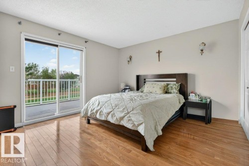 Bedroom featuring wood-finish flooring, a sliding glass door, and wall-mounted sconces - 157 Kiniski Crescent, Edmonton, AB - Indoor Photo Showing Bedroom