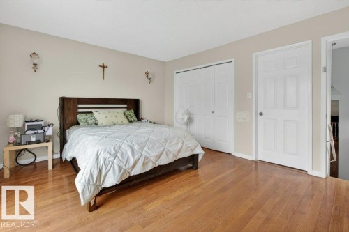 Hardwood flooring, light beige wall paint, white trim, and white bi-fold closet doors - 157 Kiniski Crescent, Edmonton, AB - Indoor Photo Showing Bedroom
