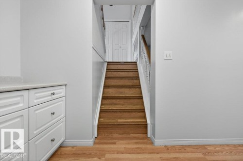 Hardwood stairs with white balusters and handrail, complemented by white wall paneling - 157 Kiniski Crescent, Edmonton, AB - Indoor Photo Showing Other Room