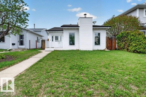White siding exterior featuring a prominent chimney, dark shingle roof, and a front porch with white railing - 157 Kiniski Crescent, Edmonton, AB - Outdoor