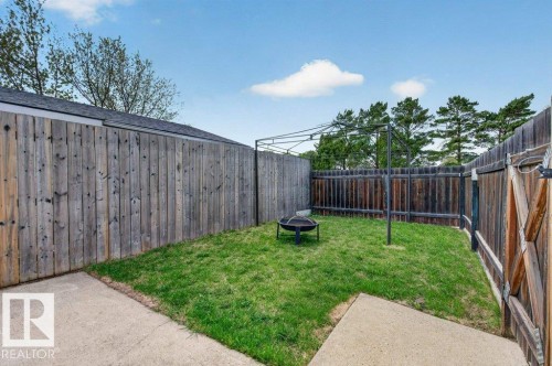 Enclosed backyard featuring a grass lawn, wood fencing, and concrete patio areas - 157 Kiniski Crescent, Edmonton, AB - Outdoor