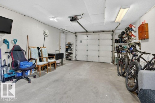 Garage space featuring a concrete floor, white panel garage door, recessed lighting, and a side-entry door - 157 Kiniski Crescent, Edmonton, AB - Indoor Photo Showing Garage