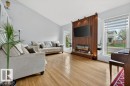 Living area featuring wood-finish flooring, a vaulted ceiling, and an accent wall with vertical wood paneling - 157 Kiniski Crescent, Edmonton, AB  - Indoor Photo Showing Living Room With Fireplace 