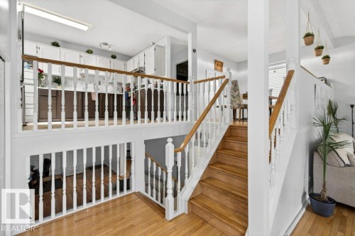 Multilevel interior featuring natural wood stair treads, white balusters, and wood-finish flooring - 157 Kiniski Crescent, Edmonton, AB - Indoor Photo Showing Other Room
