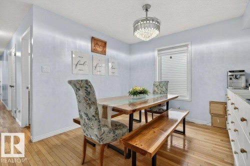 Dining area featuring hardwood flooring, a modern chandelier, and a large window with blinds - 157 Kiniski Crescent, Edmonton, AB - Indoor Photo Showing Dining Room