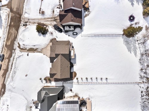 Aerial view of the property and surrounding area, showcasing the brown-roofed residence with a paved driveway and a large, snow-covered yard - 1513 Horseshoe Bay Estates, Cold Lake, AB - Outdoor