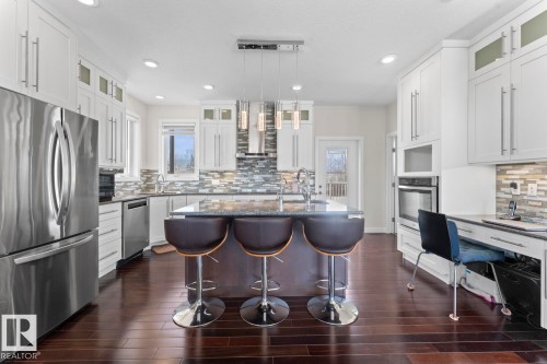 This kitchen features dark wood flooring, white cabinetry with silver hardware, and stainless steel appliances - 1513 Horseshoe Bay Estates, Cold Lake, AB - Indoor Photo Showing Kitchen With Upgraded Kitchen
