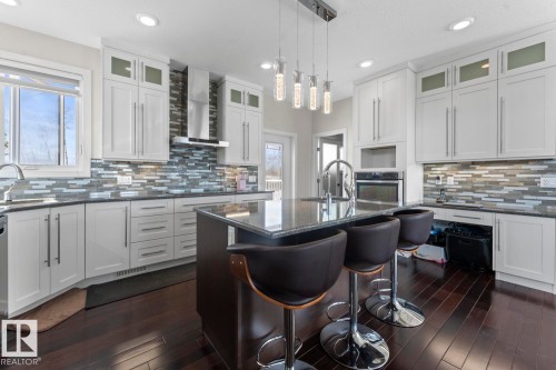 The property features a kitchen with dark hardwood flooring, white cabinetry, and a modern tile backsplash - 1513 Horseshoe Bay Estates, Cold Lake, AB - Indoor Photo Showing Kitchen With Upgraded Kitchen