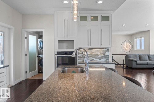 Kitchen featuring white cabinetry, a built-in oven, a stainless steel sink, and a stone countertop - 1513 Horseshoe Bay Estates, Cold Lake, AB - Indoor Photo Showing Kitchen With Double Sink