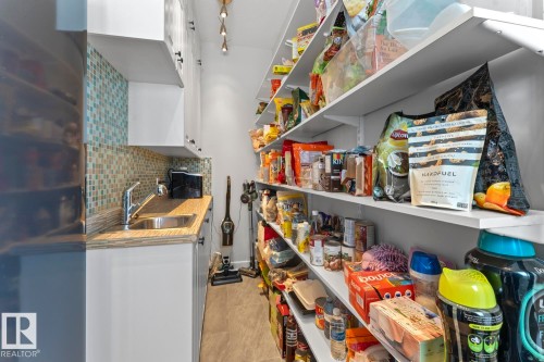 The property features a dedicated pantry space with extensive shelving, a countertop, an undermount sink with a faucet, and white cabinetry - 1513 Horseshoe Bay Estates, Cold Lake, AB - Indoor Photo Showing Other Room