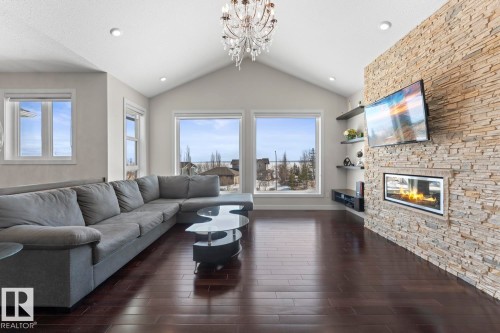 Living room featuring vaulted ceilings, a decorative chandelier, and rich hardwood flooring - 1513 Horseshoe Bay Estates, Cold Lake, AB - Indoor Photo Showing Living Room With Fireplace