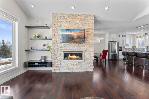 Open-concept living area featuring dark wood flooring, a stone-accented fireplace, and recessed lighting - 1513 Horseshoe Bay Estates, Cold Lake, AB - Indoor Photo Showing Living Room With Fireplace