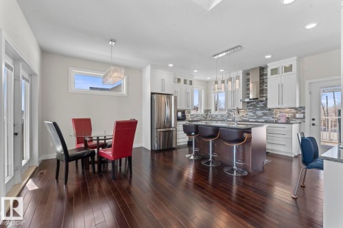 Spacious kitchen and dining area featuring dark hardwood floors, white cabinetry, stainless steel appliances, and a kitchen island with seating - 1513 Horseshoe Bay Estates, Cold Lake, AB - Indoor Photo Showing Dining Room