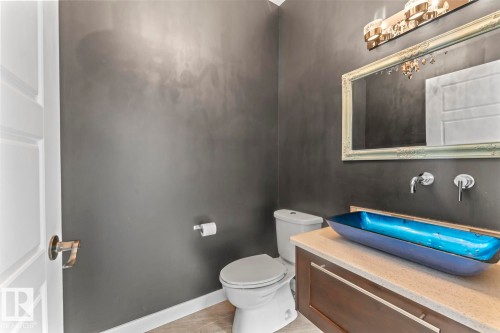This bathroom features a contemporary blue vessel sink, a vanity with a light-colored countertop, and a decorative framed mirror - 1513 Horseshoe Bay Estates, Cold Lake, AB - Indoor Photo Showing Bathroom