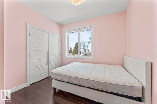 This room features hardwood floors, a window providing natural light, and a closet with white paneled doors - 1513 Horseshoe Bay Estates, Cold Lake, AB - Indoor Photo Showing Bedroom