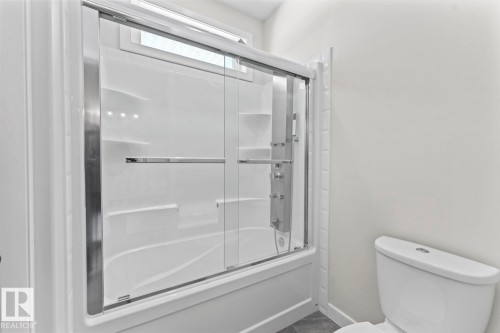 The bathroom features a combination tub and shower with glass sliding doors and a white toilet - 1513 Horseshoe Bay Estates, Cold Lake, AB - Indoor Photo Showing Bathroom
