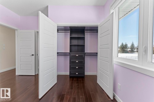 This room features dark hardwood flooring, a built-in closet organization system with shelving and drawers, and a large window providing views of the outdoors - 1513 Horseshoe Bay Estates, Cold Lake, AB - Indoor Photo Showing Other Room