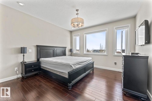 This bedroom features rich hardwood flooring, light-colored walls, and a contemporary chandelier - 1513 Horseshoe Bay Estates, Cold Lake, AB - Indoor Photo Showing Bedroom