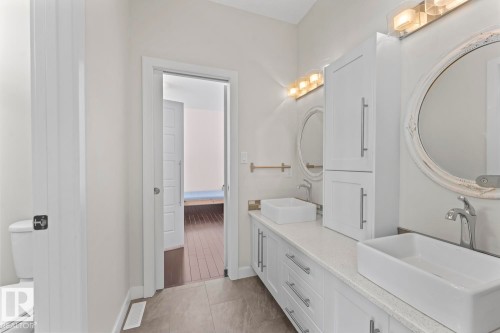 The bathroom features a double vanity with vessel sinks, white cabinetry, and two oval mirrors - 1513 Horseshoe Bay Estates, Cold Lake, AB - Indoor Photo Showing Other Room