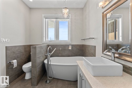 Bathroom featuring a freestanding white bathtub, a vessel sink, and a large framed mirror - 1513 Horseshoe Bay Estates, Cold Lake, AB - Indoor Photo Showing Bathroom