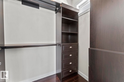 Custom closet organization system featuring dark wood cabinetry, shelving, and drawers with chrome hardware - 1513 Horseshoe Bay Estates, Cold Lake, AB - Indoor