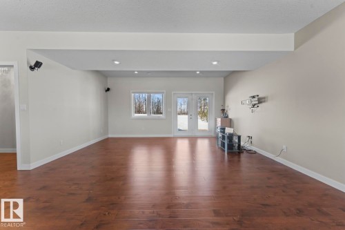 Spacious living area featuring rich hardwood floors, recessed lighting, and a window and double doors providing natural light - 1513 Horseshoe Bay Estates, Cold Lake, AB - Indoor