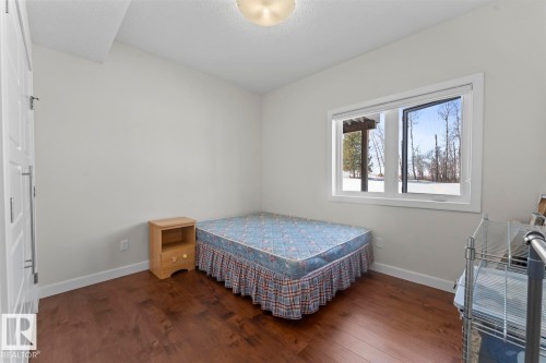 This room features hardwood flooring, white walls, and a window providing natural light and a view of the outdoors - 1513 Horseshoe Bay Estates, Cold Lake, AB - Indoor Photo Showing Bedroom