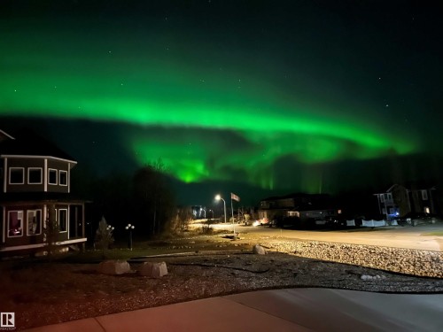 The property offers a captivating view of the night sky, featuring a vibrant green aurora borealis - 1513 Horseshoe Bay Estates, Cold Lake, AB - 