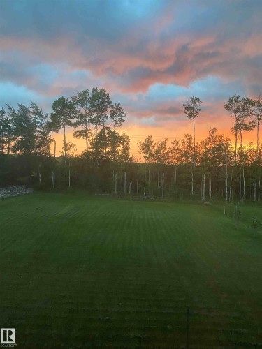 Expansive lawn area with a backdrop of mature trees, offering a serene outdoor setting - 1513 Horseshoe Bay Estates, Cold Lake, AB - Outdoor With Body Of Water With View