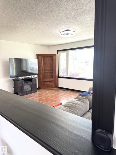 Living area featuring wood-finish flooring, a large picture window with dark trim, and a contemporary ceiling fixture - 45 Lambert Crescent, St. Albert, AB - Indoor