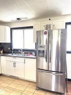 Kitchen featuring white cabinetry, a double basin sink, dark countertops, and a tiled backsplash - 