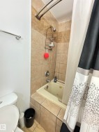 Bathtub with integrated jets surrounded by neutral-toned tiled walls and platform - 