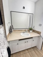 Bathroom vanity featuring white cabinetry with silver-tone hardware, a light-toned countertop, and an integrated oval sink - 