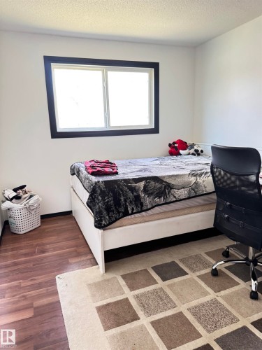 Room featuring wood-finish flooring, a double-pane window with dark trim, and light-colored walls - 45 Lambert Crescent, St. Albert, AB - Indoor Photo Showing Bedroom