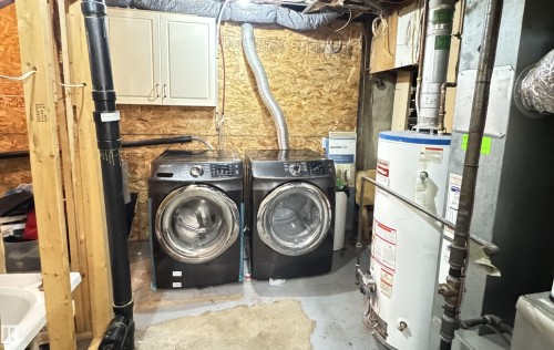 Dedicated laundry area featuring a front-loading washer and dryer, wall-mounted cabinetry, and a utility sink - 45 Lambert Crescent, St. Albert, AB - Indoor Photo Showing Laundry Room