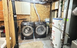 Dedicated laundry area featuring a front-loading washer and dryer, wall-mounted cabinetry, and a utility sink - 