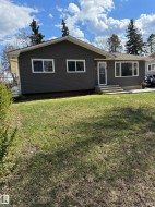 Ranch-style residence featuring dark gray horizontal siding, white trim, and a prominent front lawn - 