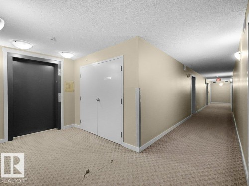 Interior building corridor featuring patterned carpeting, neutral wall paint, white trim, and flush-mount lighting fixtures - 216 5390 Chappelle Road, Edmonton, AB - Indoor Photo Showing Other Room
