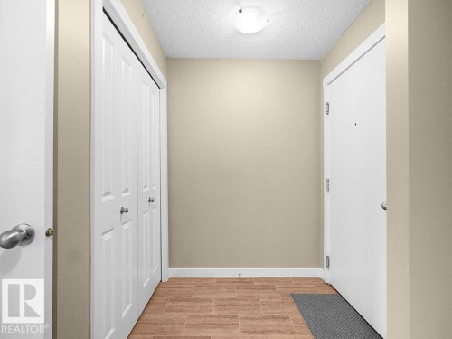 Entryway featuring wood-finish tile flooring, a white paneled entry door, and a flush-mount ceiling light fixture - 216 5390 Chappelle Road, Edmonton, AB - Indoor Photo Showing Other Room