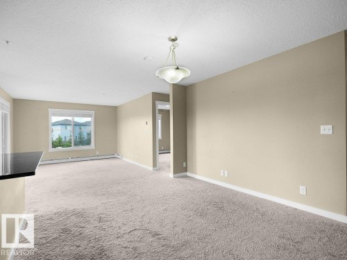 Spacious room featuring neutral carpeting, light beige walls, and white trim - 216 5390 Chappelle Road, Edmonton, AB - Indoor Photo Showing Other Room